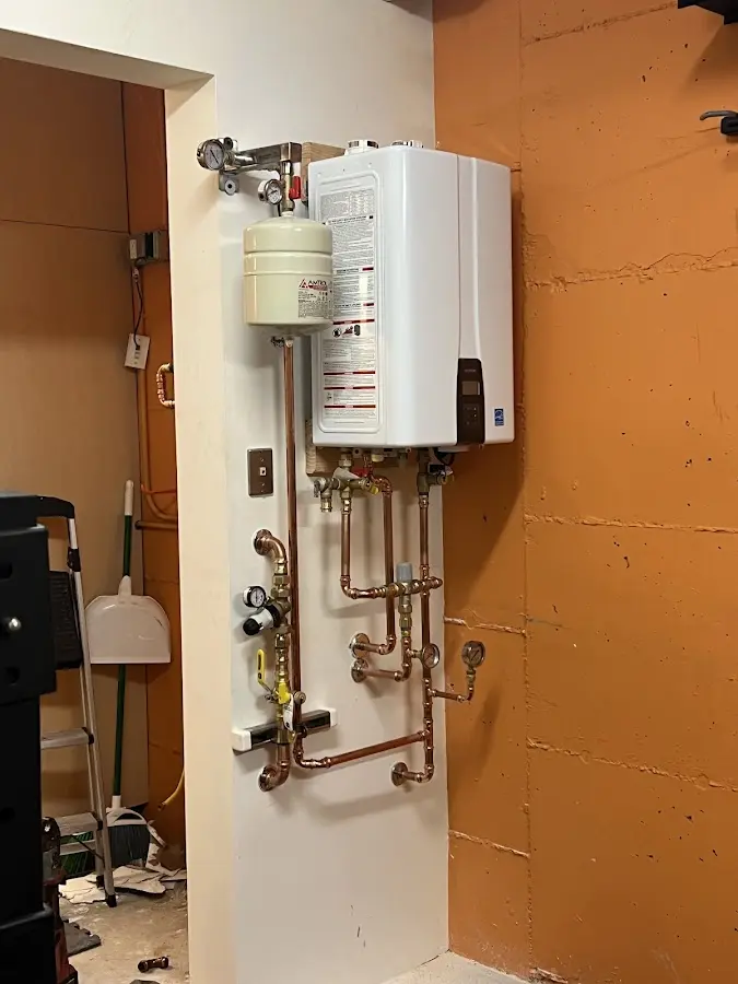 Plumbing technician inspecting water heater connections in Zillah